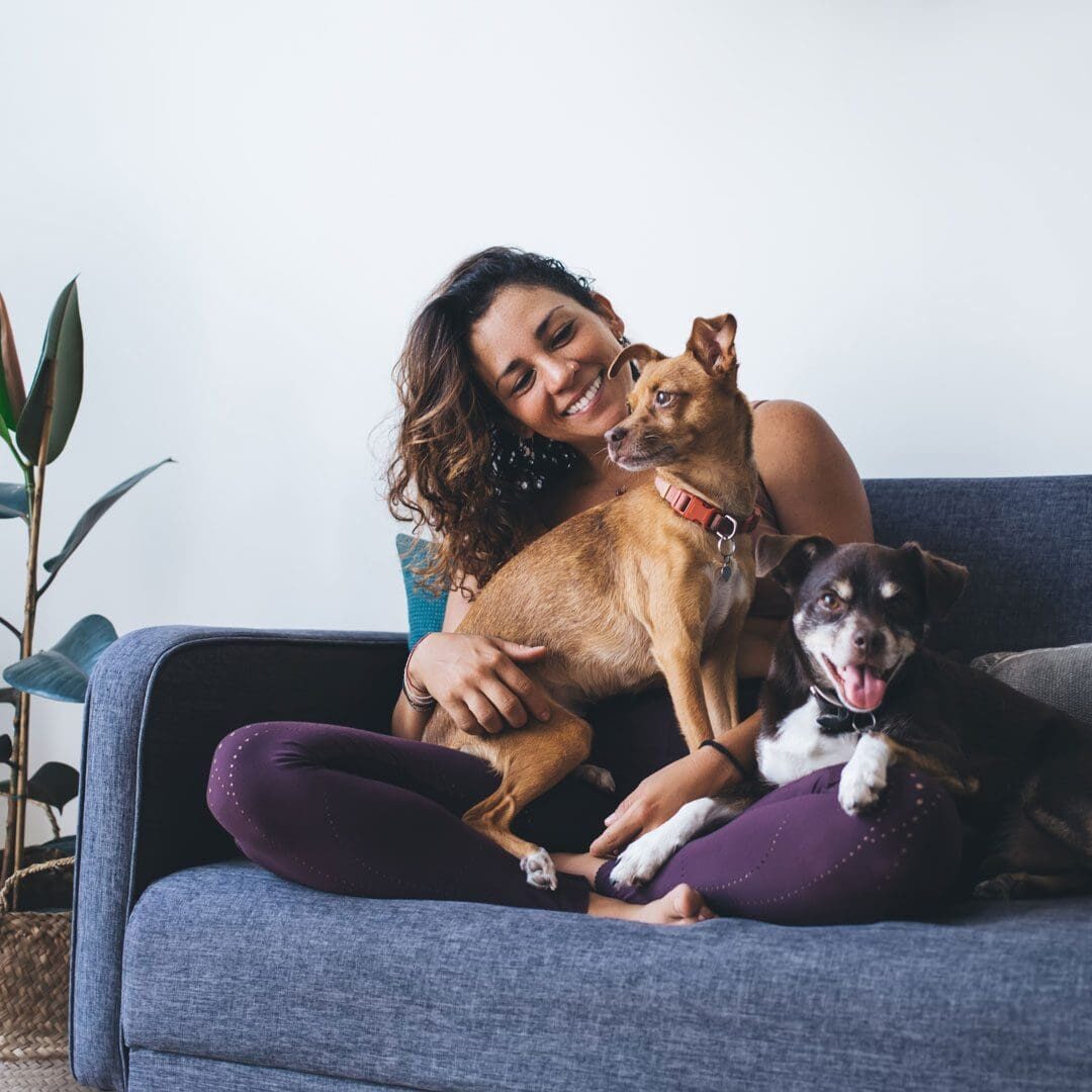 Woman Sitting On The Couch With Her Dogs And Smiling